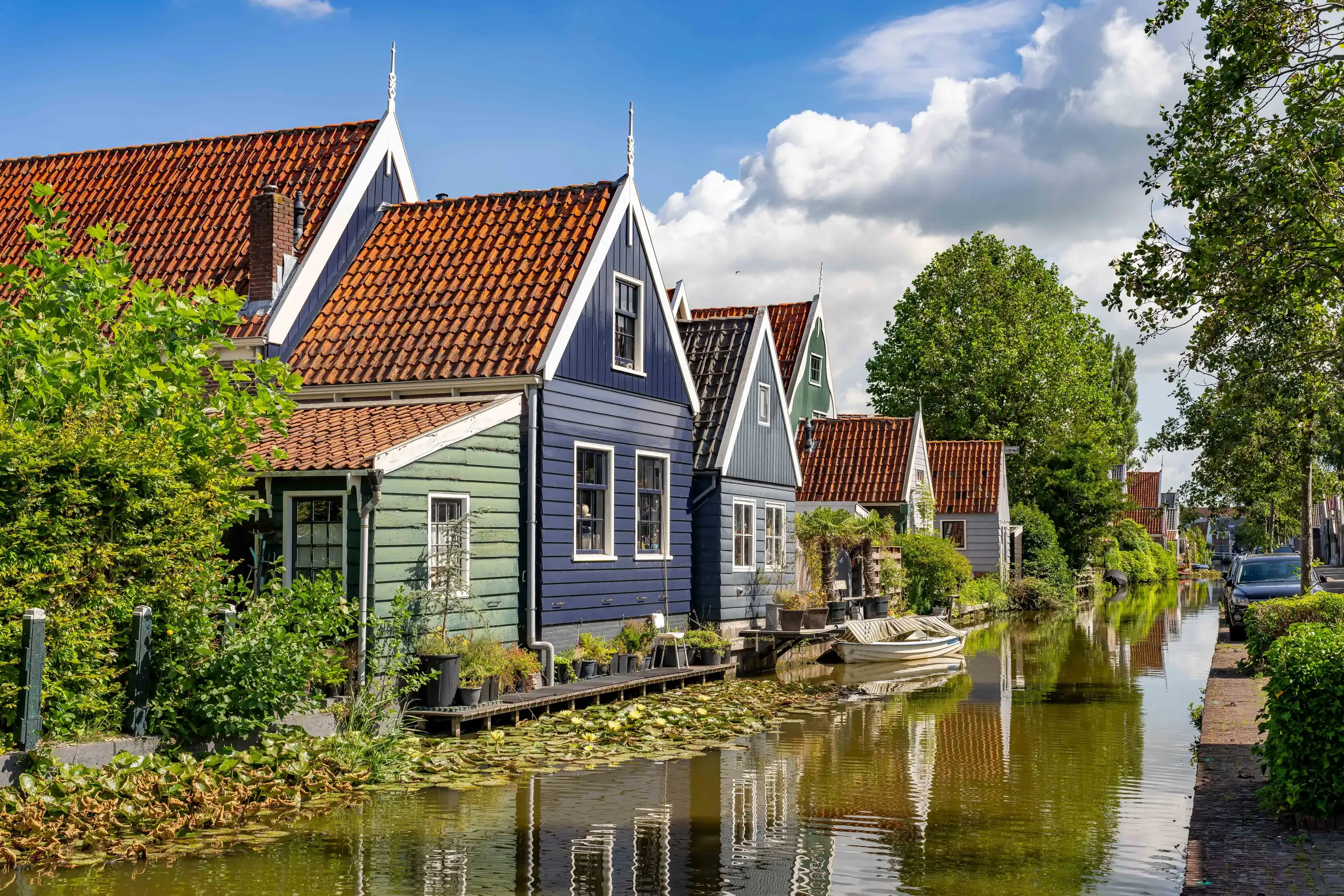 Huizen aan het water met volle, groene bomen eromheen